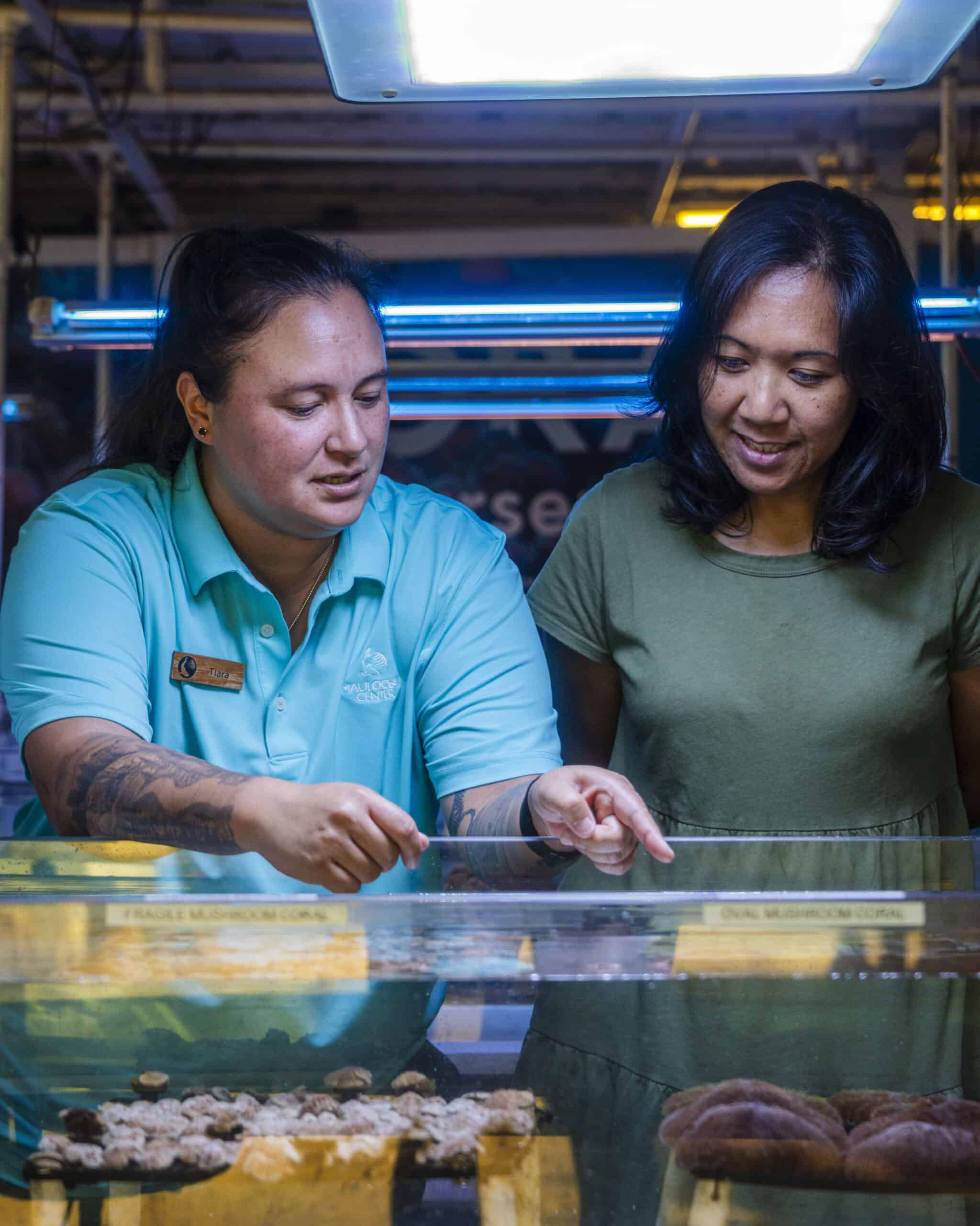 Two women at Maui Ocean Center examining marine life displays.